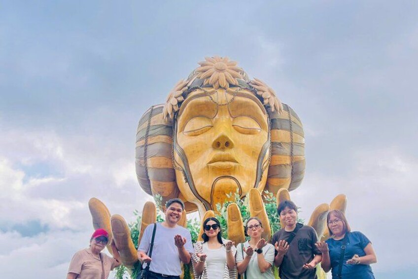 Una gran escultura de un rostro con tocado, rodeada de gente. 3