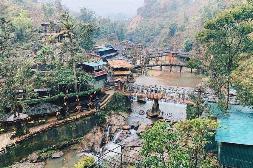 A mountainous village with traditional houses, a river, and a bridge. 2