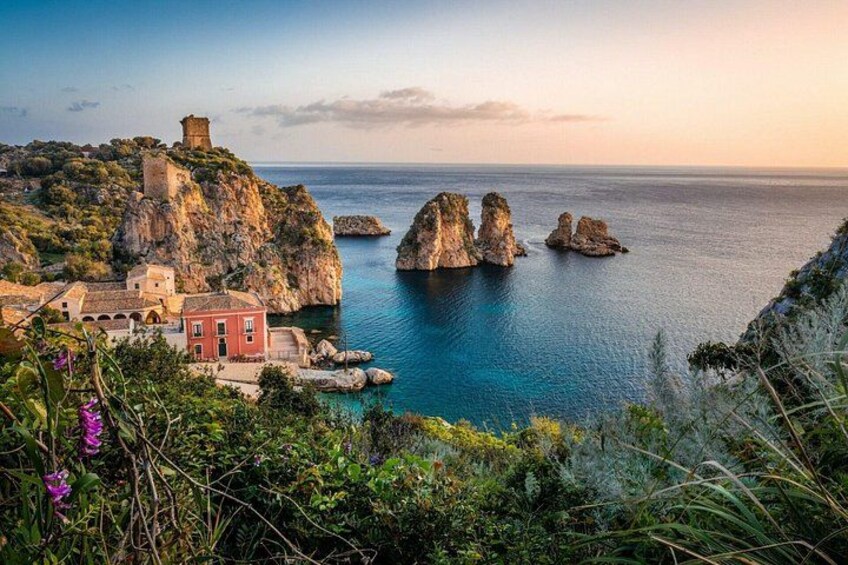 Un paisaje costero con un edificio rojo, acantilados rocosos y una torre. 1