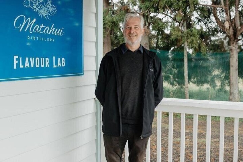 A man standing on a porch with a sign for Matahui Distillery's Flavour Lab. 2
