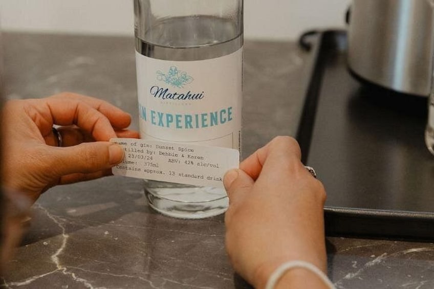 Una persona sostiene una botella de Ginebra Matahuti Experience con una etiqueta que detalla su contenido y origen. 2