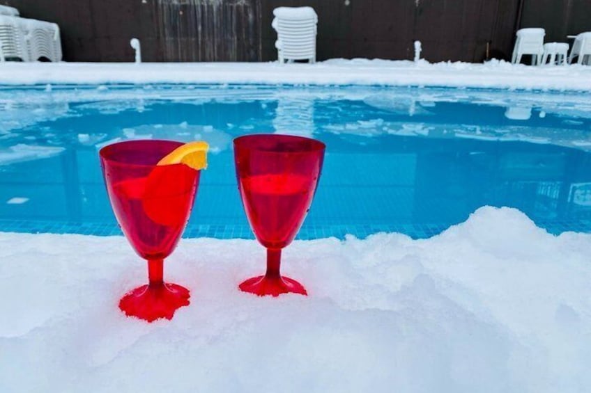 Twee rode glazen met een gele plak op een besneeuwd oppervlak nabij een zwembad. 1