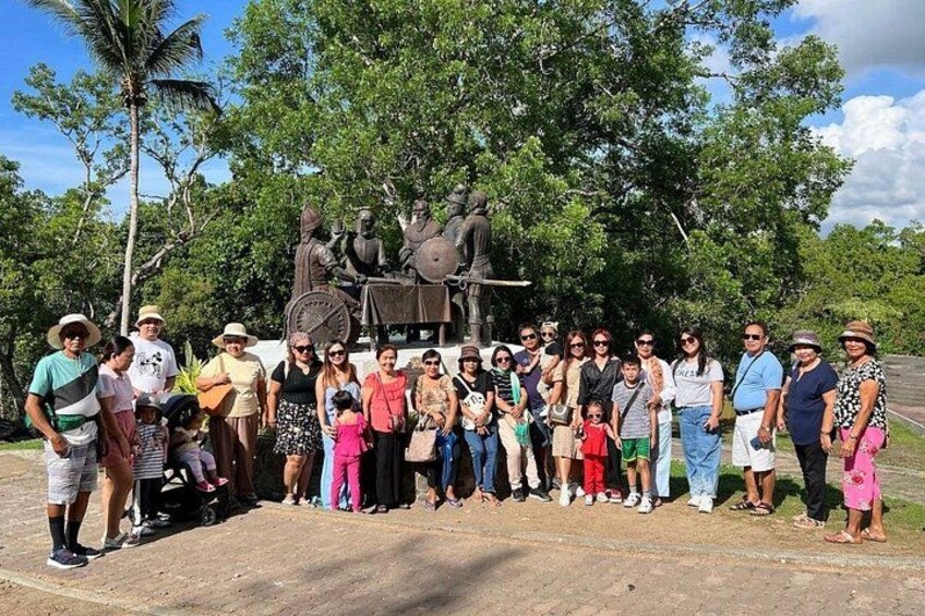 A tour group stands in front of the historic Blood Compact Monument in Bohol, surrounded by lush greenery and historical sculptures. 5