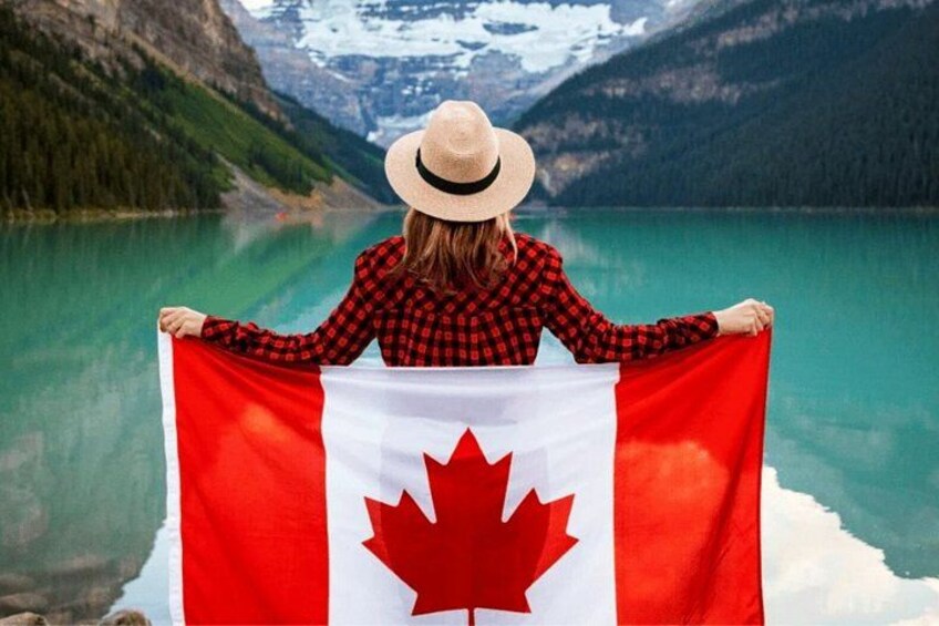 A person holding a Canadian flag with a mountainous landscape in the background. 2