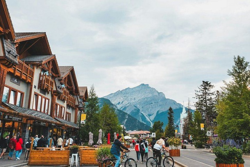 A mountain town with wooden buildings, people walking, and a mountain in the background. 5