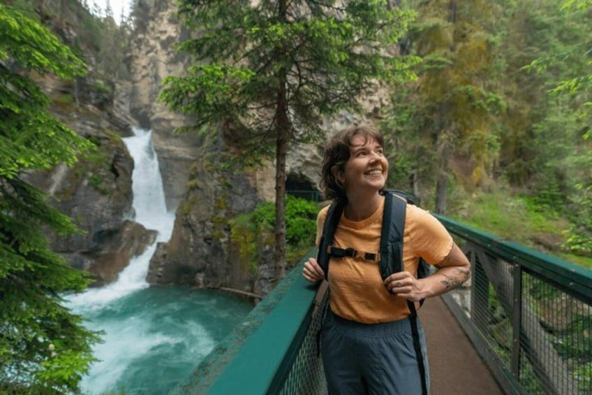 A person hiking on a bridge with a waterfall in the background. 3