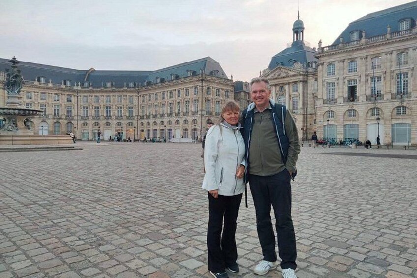 A historic building with a courtyard, a fountain, and people standing in front. 5