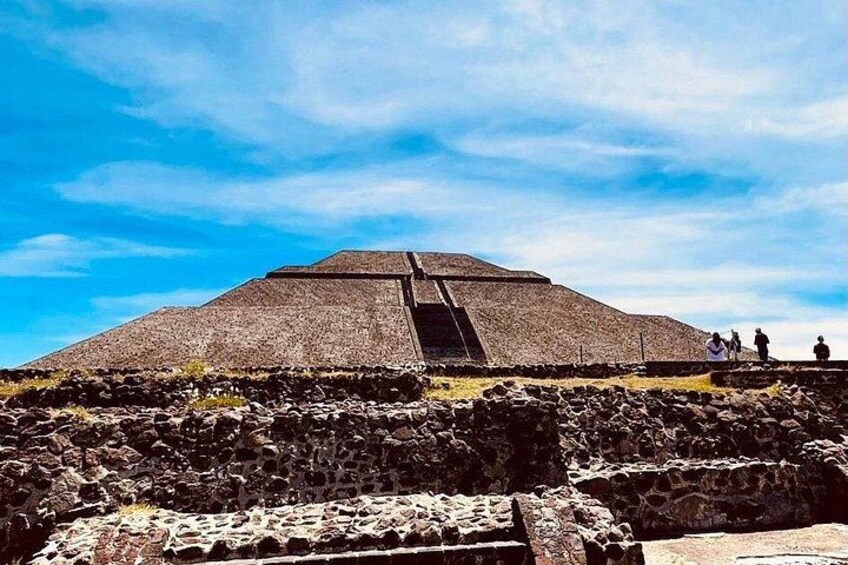A large pyramid structure with a staircase leading to the top, surrounded by rocky terrain and a clear sky. 5