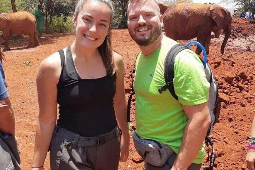 Deux personnes se tiennent sur un chemin de terre, avec des éléphants en arrière-plan. 5