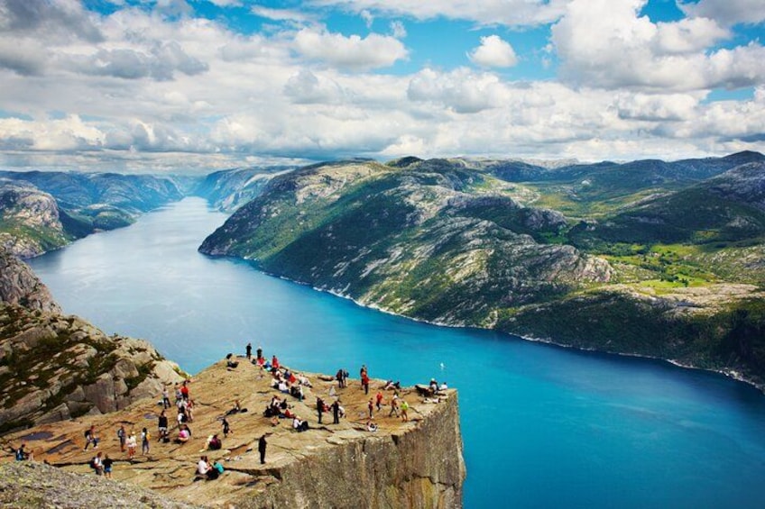 A mountainous landscape with a lake, a cliff with people, and a clear sky. 2