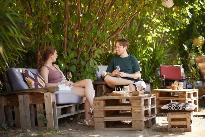 Two people sitting on a wooden bench outdoors, surrounded by greenery. 4