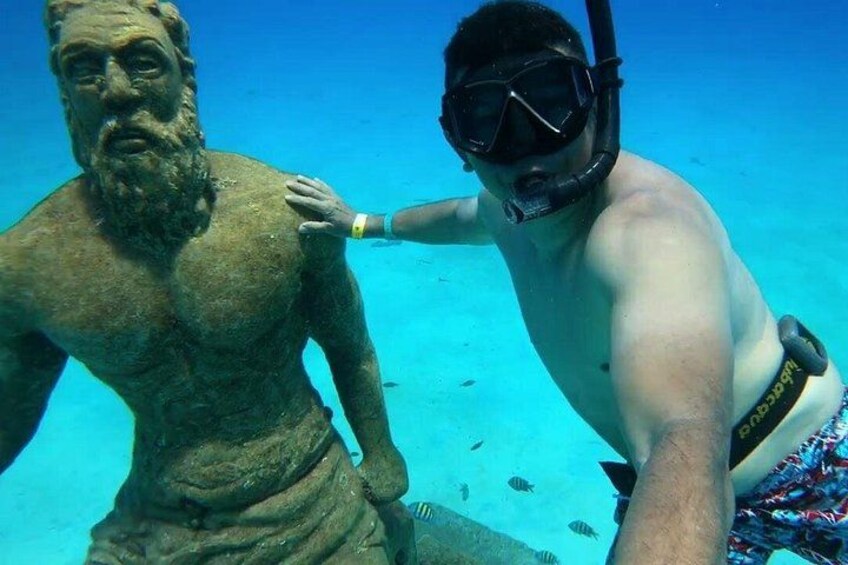 A diver with a snorkel and fins, a statue, and clear blue water. 2