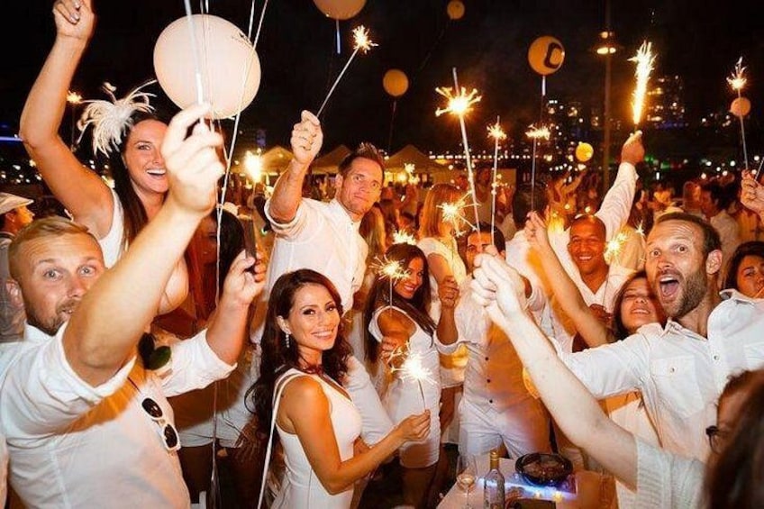 A group of people holding sparklers at a nighttime event. 1