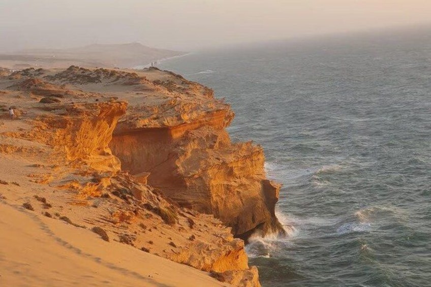 A coastal landscape with a prominent rock formation and a sandy beach. 1