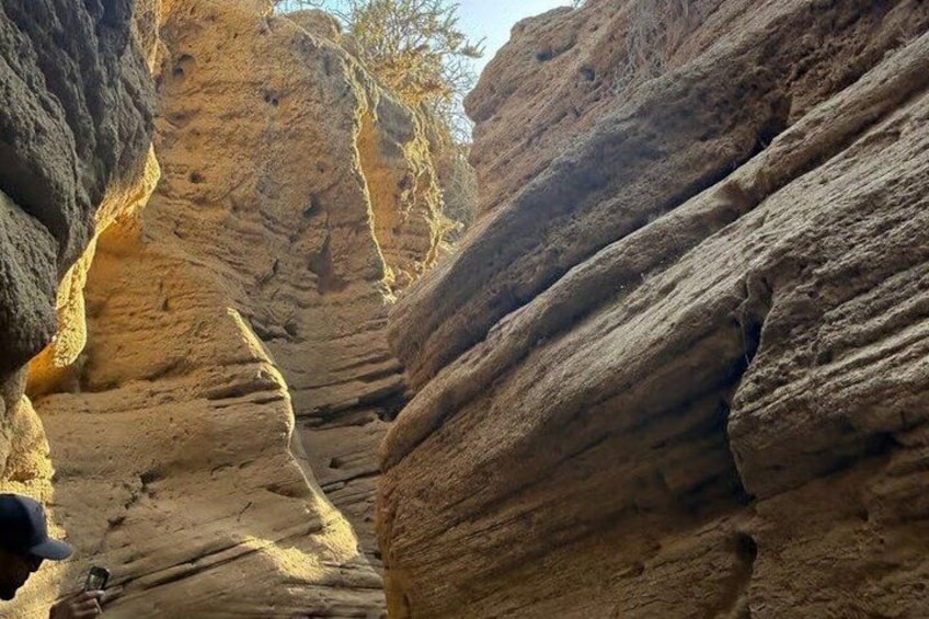 A canyon with layered rock formations and a narrow passageway. 5