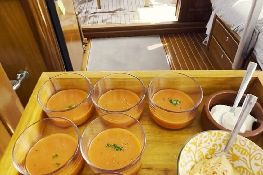 A wooden tray with bowls of soup and a plate with a spoon. 3
