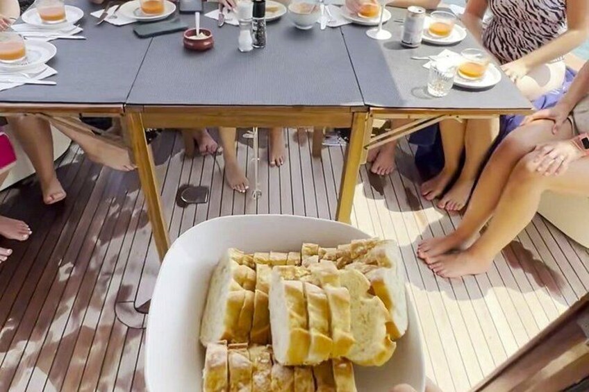 A group of people dining at a table with a box of bread and various dishes. 2