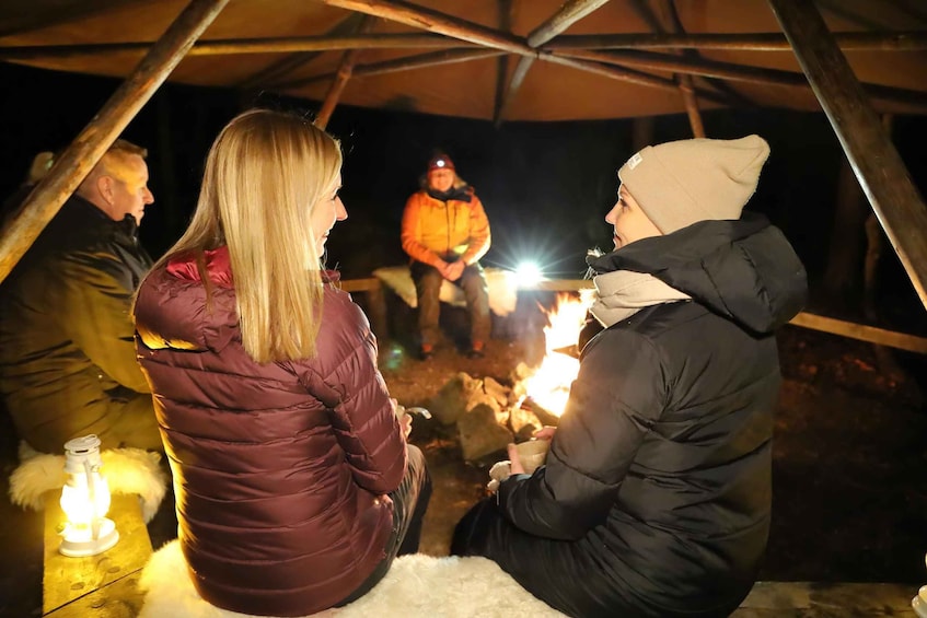 People sitting around a campfire inside a tent. 1