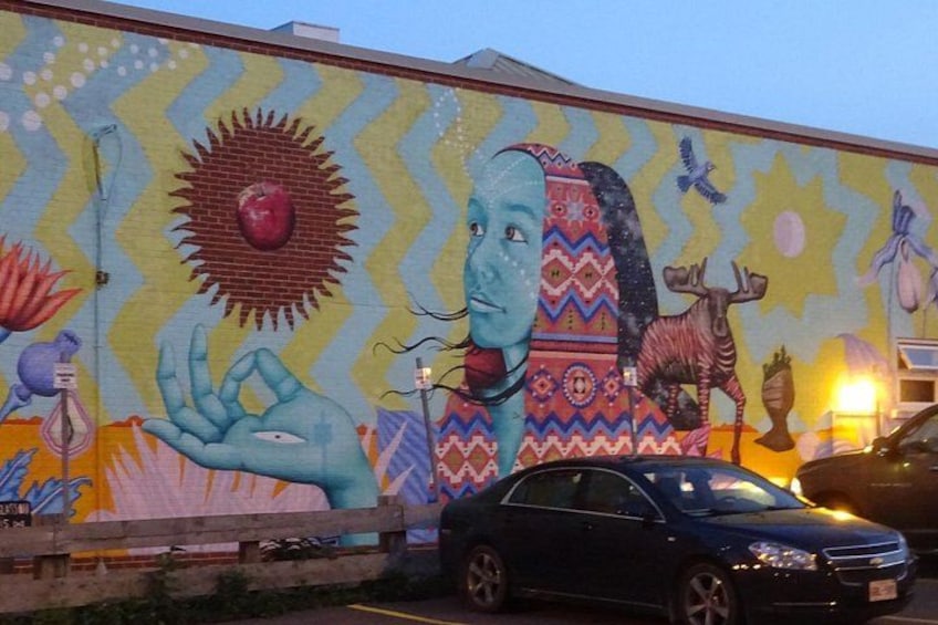 A mural with a large hand, a sun, and a moose on a building. 2
