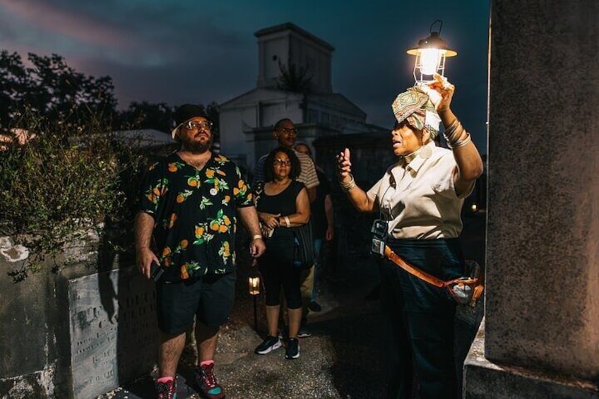A group of people standing outdoors at night, one holding a lantern. 2