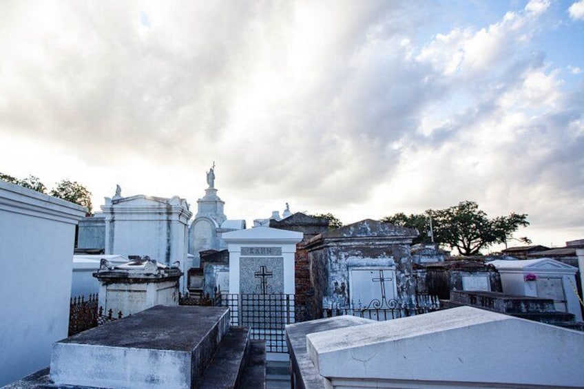 A cemetery with various tombstones and crosses, surrounded by trees and under a cloudy sky. 5