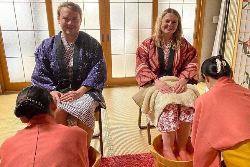En traditionell japansk miljö med tatamimattor på golvet, en shoji-skärm och en person klädd i en lila kimono. 1