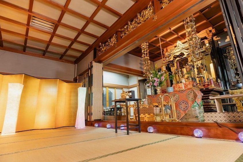 En traditionell japansk inredning med tatamimattor på golvet, ett träpanelat tak och ett altare med utsmyckade dekorationer. 2