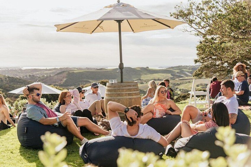 People relaxing on bean bags in a grassy area with a view of rolling hills. 4