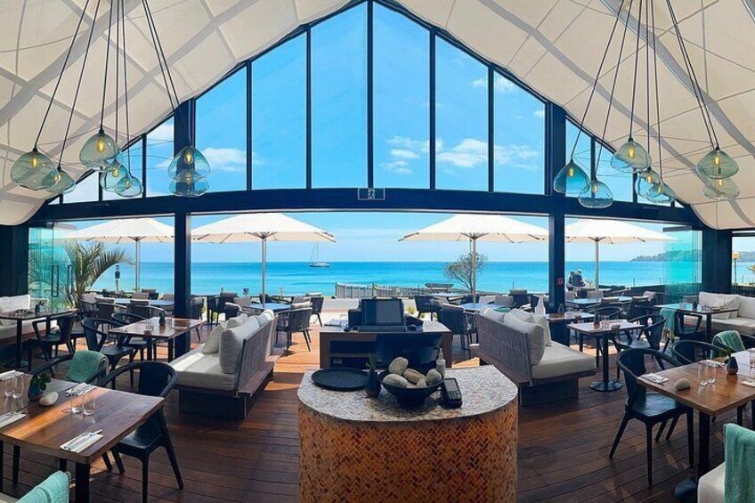 A spacious outdoor dining area with large windows overlooking the ocean. 1