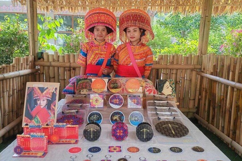 Dos personas con vestimenta tradicional junto a una mesa que exhibe diversos objetos culturales. 2