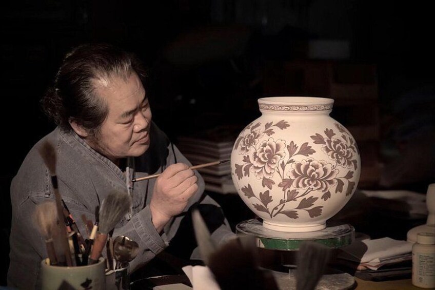 Una persona pintando un jarrón de cerámica. 3
