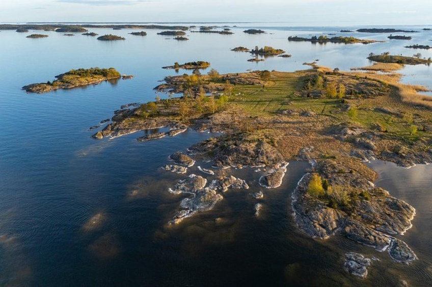 An aerial view of a coastal landscape with numerous small islands and rocky outcrops surrounded by calm water. 1