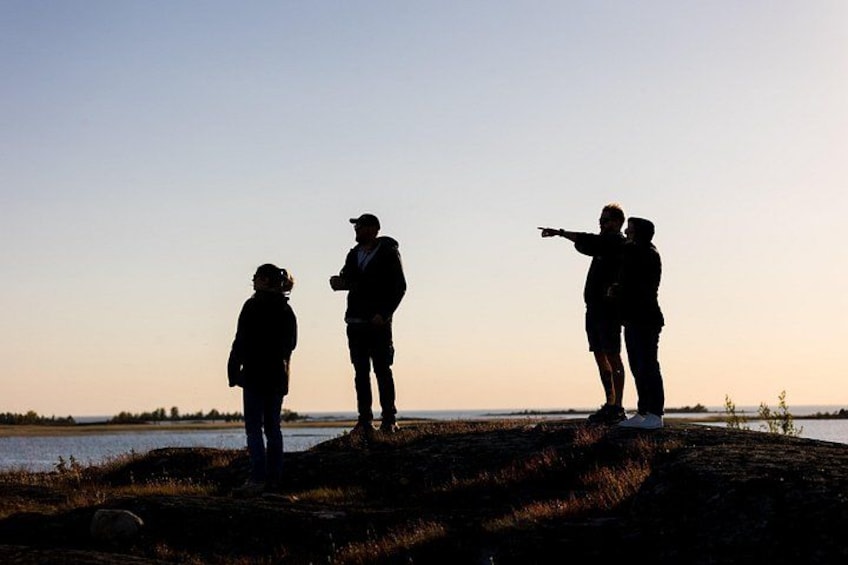 Three people standing on a hill overlooking a body of water during sunset. 5
