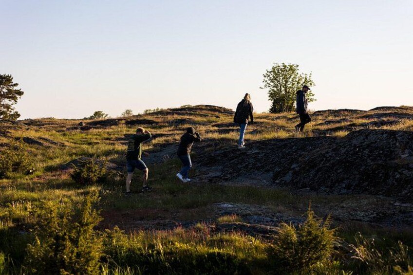Eine Gruppe von Wanderern auf einem grasbewachsen Hügel, im Hintergrund Bäume. 3