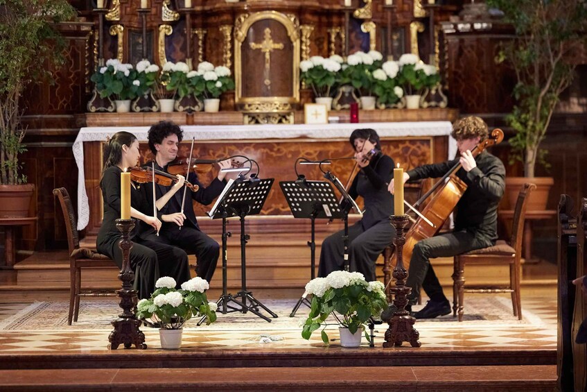 A string quartet performing in a church with ornate woodwork and floral decorations. 2