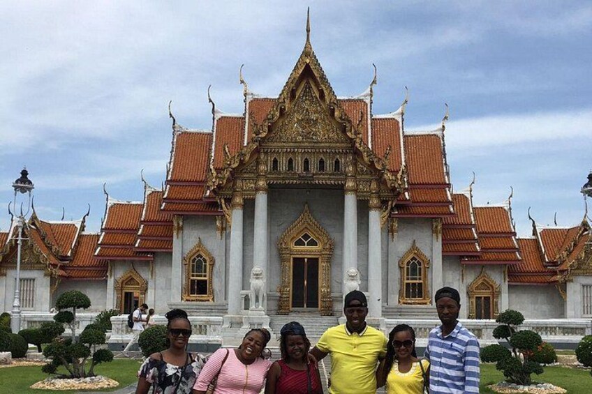 Un groupe de personnes se tient devant un temple imposant, doté d  ’une architecture richement décorée et d’un toit traditionnel. 3
