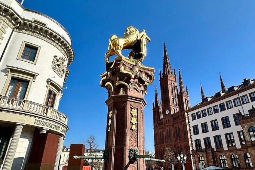 A historic building with a lion statue, a church with spires, and a modern building with a balcony. 2