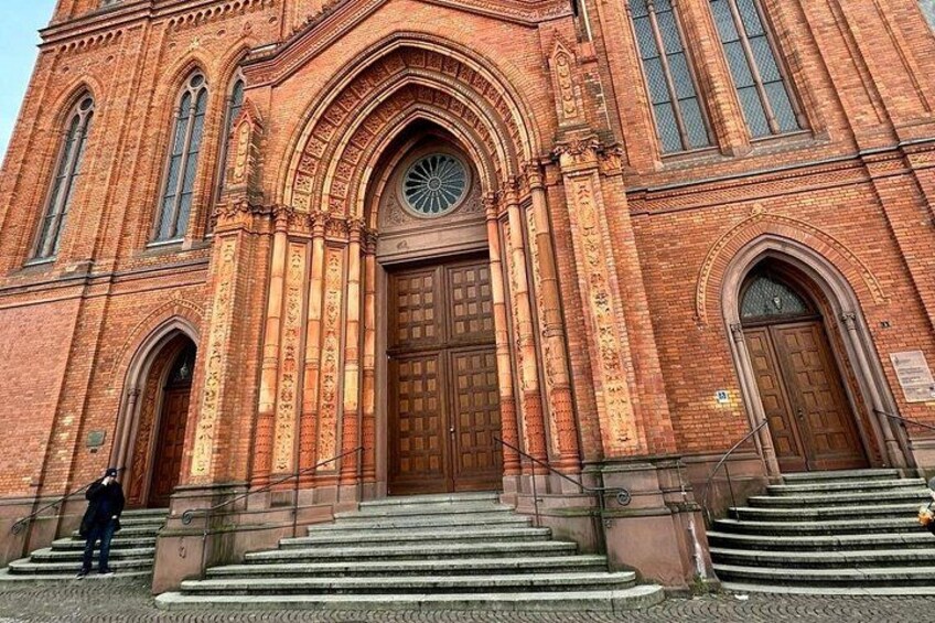 A large brick building with a prominent arched entrance and steps leading up to it. 4