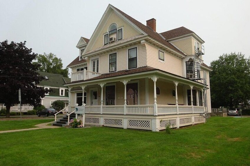 A two-story house with a porch, a chimney, and a small garden. 2