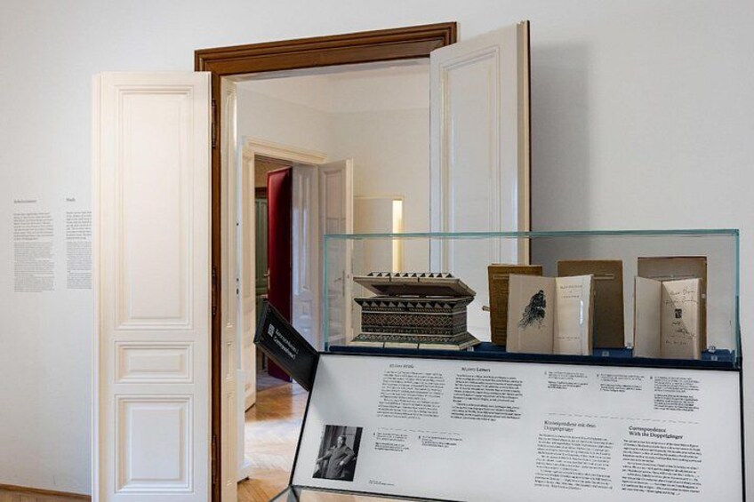 An art exhibition with a glass display case containing books and a model. 3