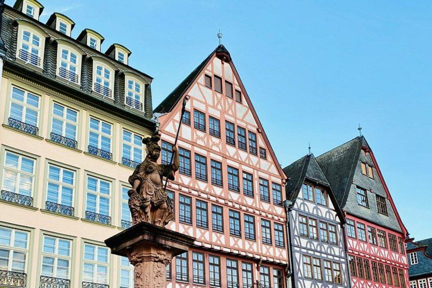 Une rangée de maisons traditionnelles à colombages, avec une statue au premier plan. 2