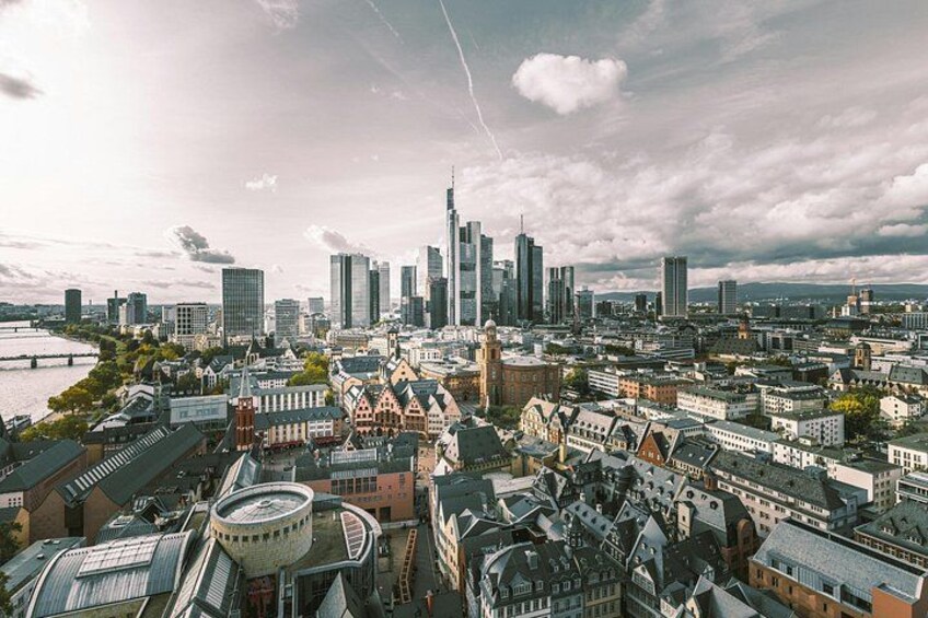 Un paysage urbain avec des bâtiments historiques et des gratte-ciel modernes, une rivière et un ciel nuageux. 5