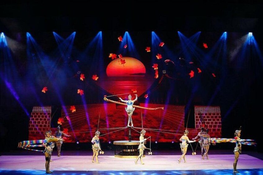 A circus performance with acrobats on a stage, illuminated by spotlights and featuring a large red backdrop. 3