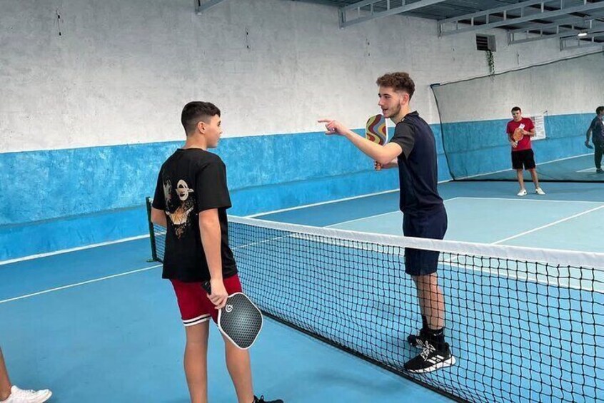 Two people on a tennis court, one holding a racket and the other pointing. 2