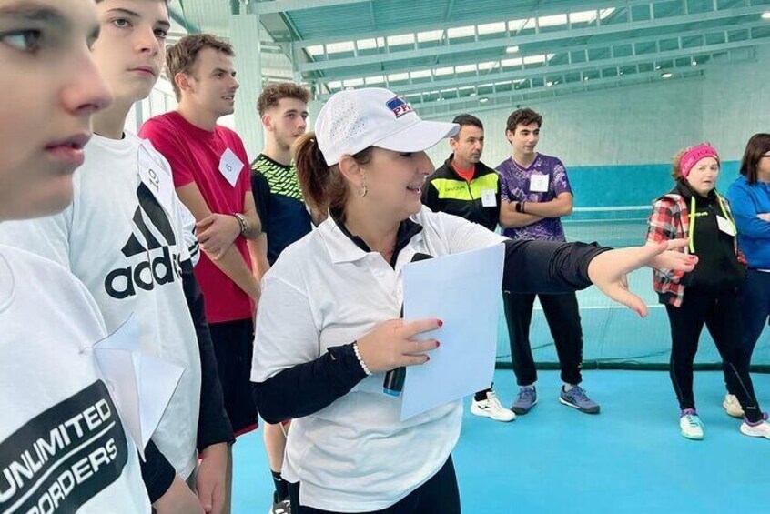 A group of people in a sports facility, some wearing sports attire and holding papers. 3