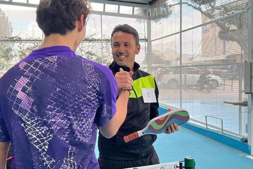 Two people in a sports facility, one holding a shoe. 1