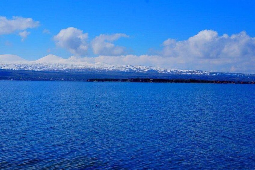 Een kalm meer met besneeuwde bergen in de verte, onder een heldere blauwe lucht. 2