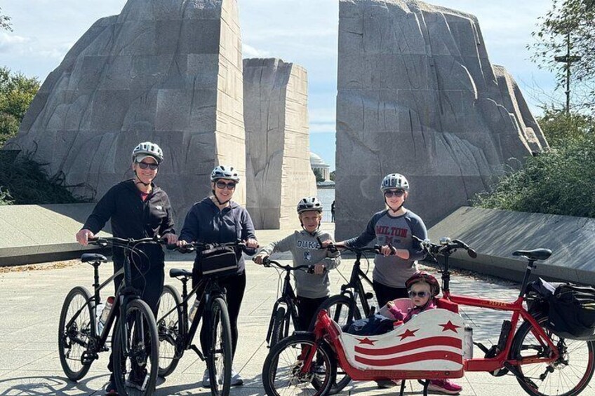 Eine Gruppe von Menschen mit Fahrrädern vor einer großen Felsformation. 2