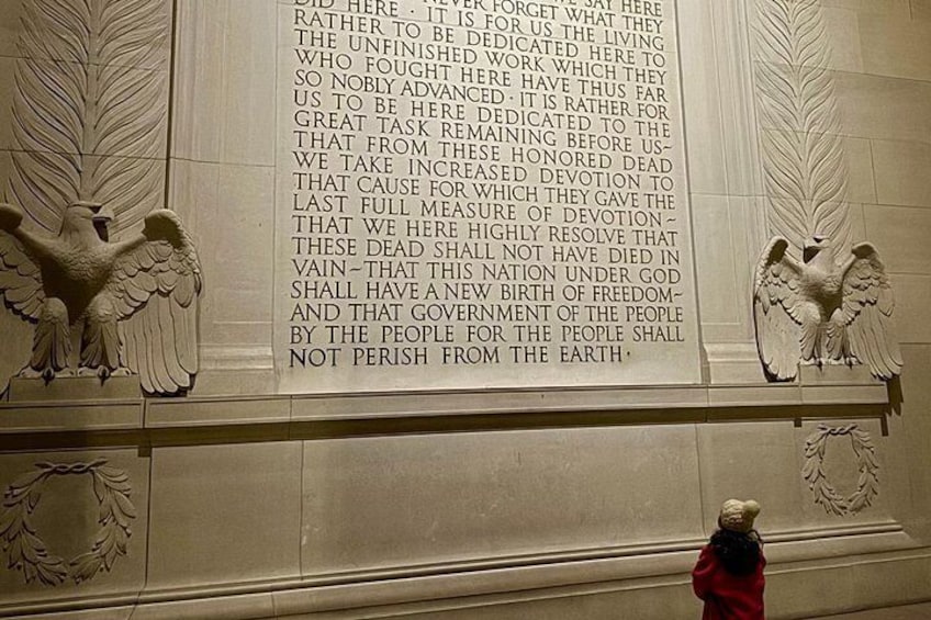 Eine Marmorwand mit eingraviertem Text und zwei Engelstatuen. 3