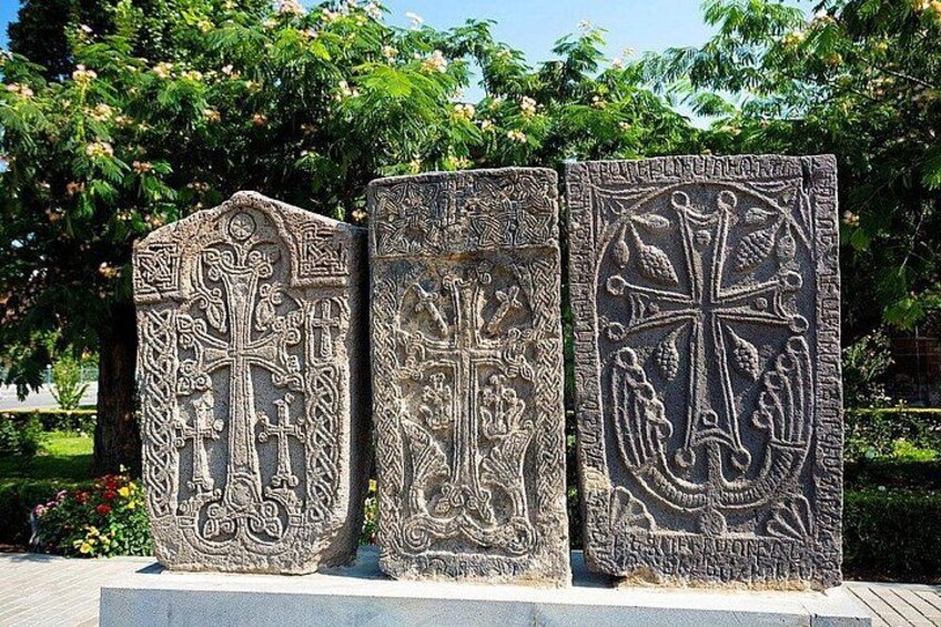 Tre monumenti in pietra con elaborate incisioni, sullo sfondo di alberi e cielo sereno. 3